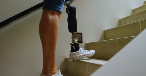 Disabled woman with prosthetic leg moving upstairs at home 4k