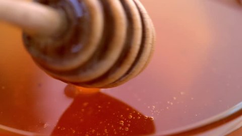 Honey dripper in bowl with liquid fresh organic honey, macro shot 库存视频