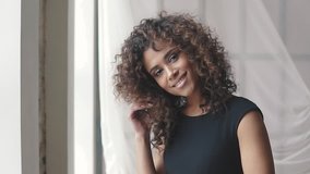 portrait of a charming hispanic girl in a black dress. curly brown girl