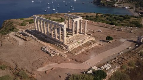 Athens Greek temple of Poseidon in morning light. Aerial drone view. Blue ocean and sailing boats in background. Cape Sounion one of the major monuments of the Golden Age of Athen. 