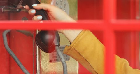 closeup view of female hand taking black hanged telephone handset in red retro payphone call box and then looking at cameraa big big surprised eyes traveling attracrive blonde woman having fun