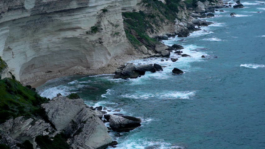 Coastline of Corsica with crashing waves and beautiful nature on cloudy day in slow motion	