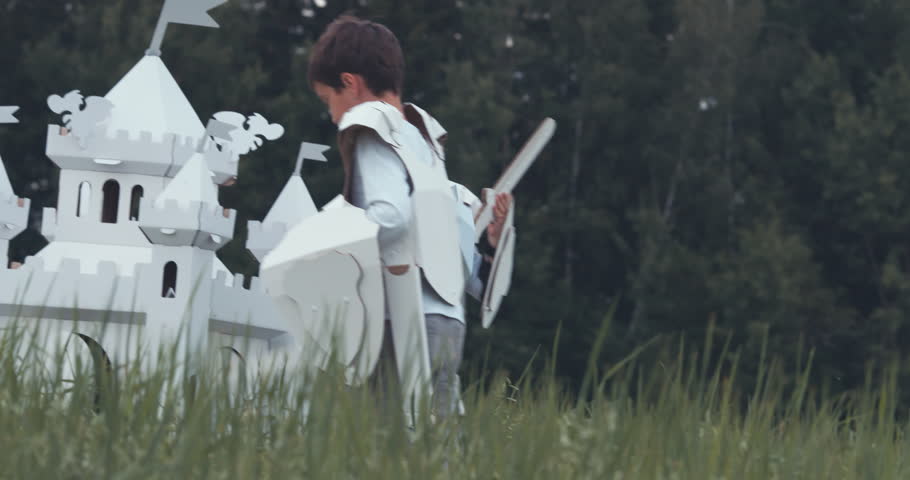 Brothers boys wearing handmade medieval knight armor costumes playing near cardboard castle. 4K UHD 60 FPS SLO MO