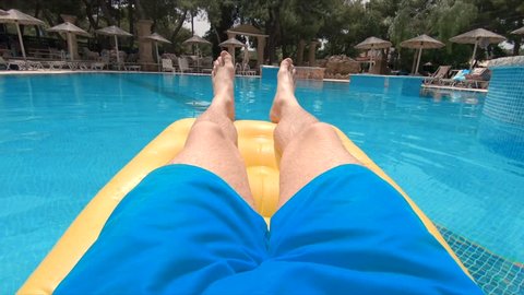 Man Relaxing On Holiday Point of View POV In Resort Pool On Lilo 4K. A Variety Of 4K Camera Angles Available.