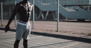Sporty African American man doing squats outdoors near the sports stadium. Workout, fitness, health, beauty, motivation concept. Shot in Red Epic