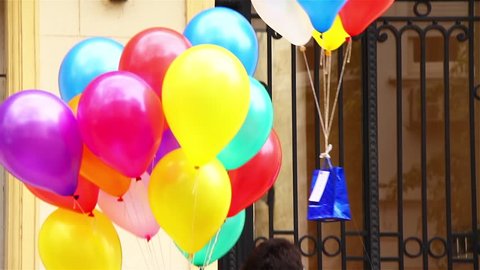 Balloons of Different Colours with a Gift flying towards a Girl at the Balcony. Declaration of Love like Romeo and Juliet or Valentines Day Concept.  