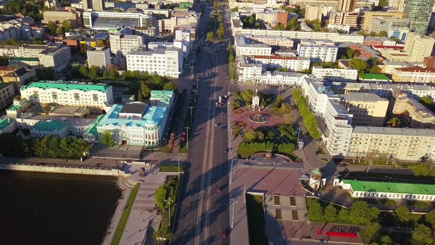 Panorama of the central street of the city of Yekaterinburg. Lenin Avenue stretches through the urban core as a wide, tree-lined arterial road flanked by mid-rise residential and administrative buildings in a mix of Soviet-era and modern styles. The aerial perspective captures the avenue