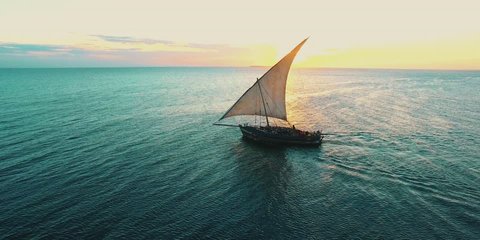 fishermen's wooden dhow sailing at sunset in Zanzibar