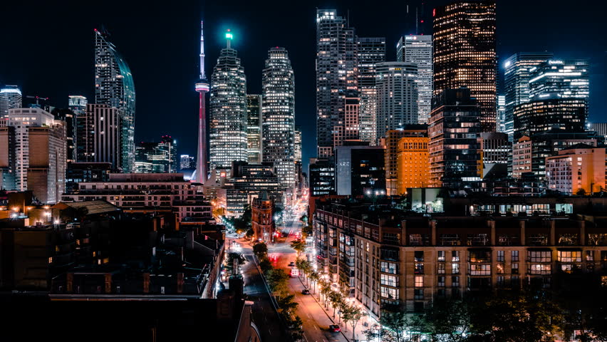 Time lapse of the St Lawrence Market tourist district of downtown Toronto with modern and futuristic financial district office building skyscrapers with car traffic light streaks. 