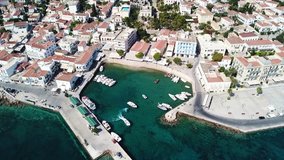 Aerial drone bird's eye view video of picturesque small harbor in historic and traditional island of Spetses with emerald clear waters, Saronic Gulf, Greece