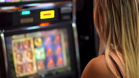 young caucasian woman plays slot machines and stands to celebrate her win