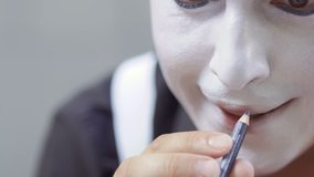 Man mime paint his lips with black pencil