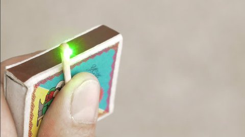 A guy is lighting a matchstick with a green laser beam. This is the easiest and most common way to produce fire through a matchbox. Vertical format video.