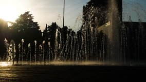 Children's silhouettes play in the city's fountain on a summer day. 4k.