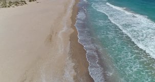 Aerial footage of drone flying over beautiful empty beach, aerial  seaside landscape with sea and waves
