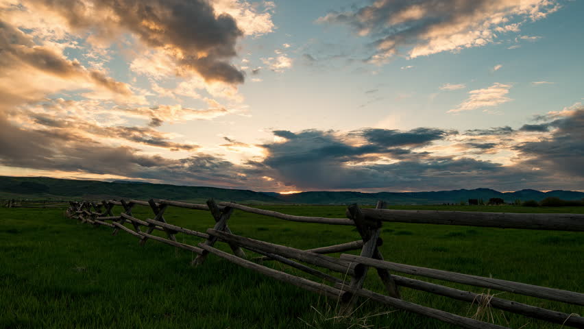 Time lapse of colorful sunset along wood fence in pasture in Star Valley Wyoming.
