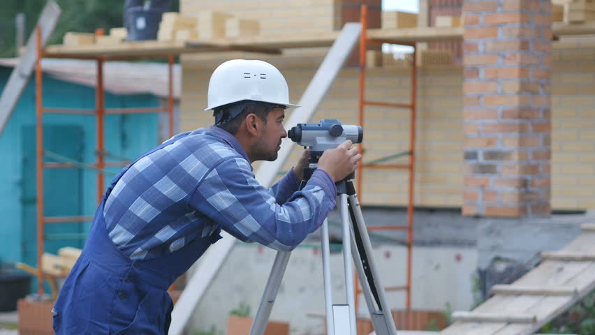 Surveyor performs measuring operations on the level and the theodolite Royalty-Free Stock Footage #1012424216