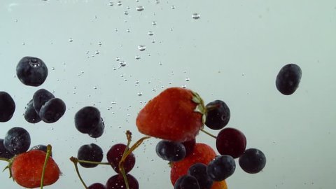 Fresh blueberry, cherry and strawberry fall into water. Slow motion. Tasty wildberries  drops into water. 