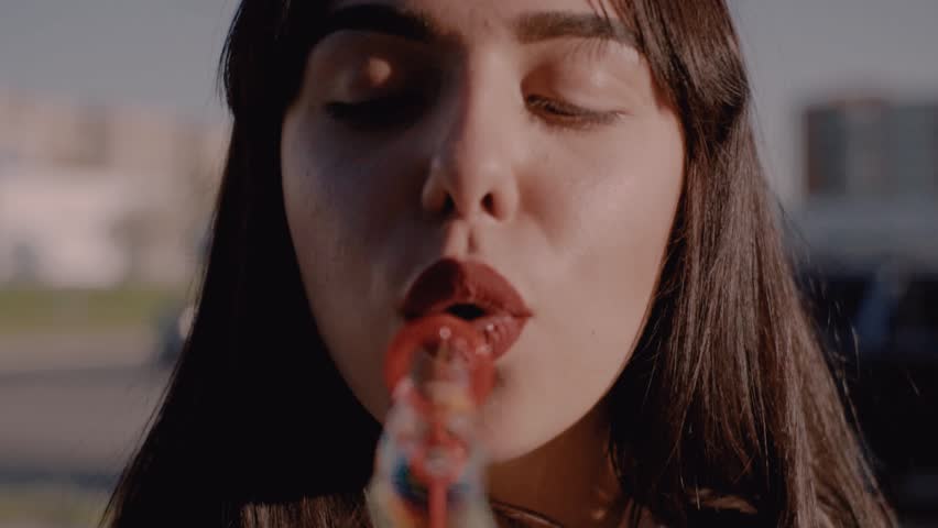 Good-looking Ukrainian girl with brown eyes blowing soap bubbles. Cheerful Caucasian girl with beautiful smile looking at camera. Close-up. Street. Summertime.