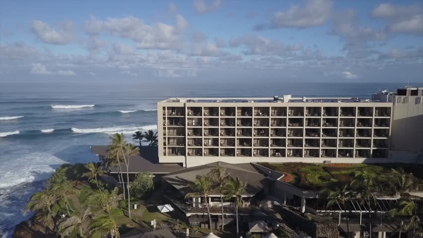 Turtle Bay Resort hotel in Oahu Hawaii north shore with pool and ocean around. solar panels on the rooftop. Tropical garden with palm trees. Aerial drone shot