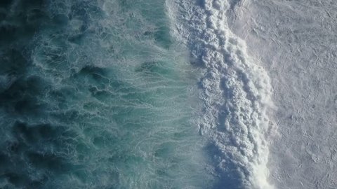 Big Waves rolling from above. Top down 4k drone view on blue turquoise ocean, breaking waves, whitewash. Sunny day over the sea. Huge swell hitting shoreline. Powerful waves Oahu, Hawaii North Shore