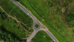 Panoramic bird's-eye aerial view of traffic navigating a small road roundabout in the UK.
