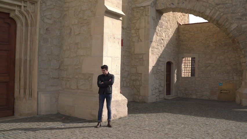 Young man meeting his girlfriend next to an old stone building.
