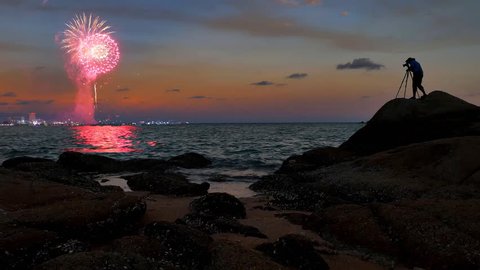 Photographer standing on the beach rock and take a photo to fireworks on nighttime