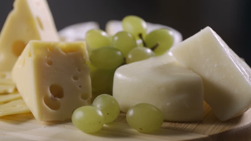 Honey is poured onto a cheese plate with different cheeses, grapes and nuts. Perfectly suited to wine, delicacy Royalty-Free Stock Footage #1012466189