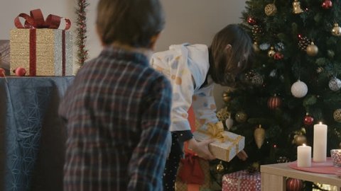Children in pyjamas picking Christmas presents on the Christmas morning
