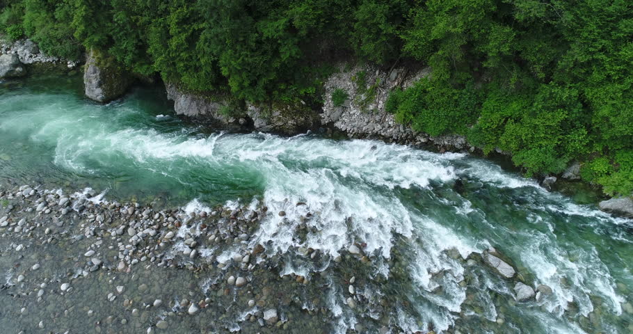 3 rafts descend an alpine river between rapids and rocks. White water rafting on Sesia river, Piedmont, Italy.