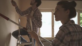 Happy couple renovating their new house and painting interior walls together: lifestyle, home makeover and remodeling concept - Powered by Shutterstock - Get 15% off with code: PIKWIZARD15