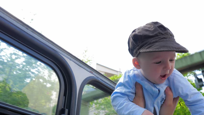 kid with pretty face on mothers arms in backlight on background of green trees in slow motion