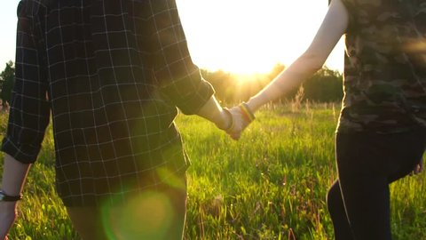 two girls walking hand in hand on the field at sunset, sun, LGBT symbol,slow mo