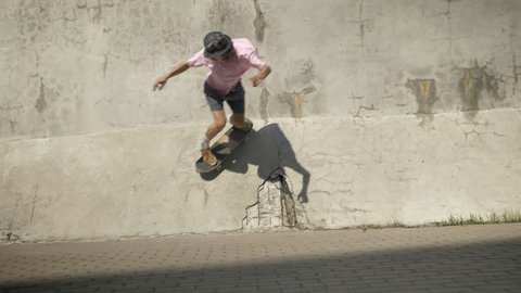 Stylish skateboarder doing skateboard trick on old wall