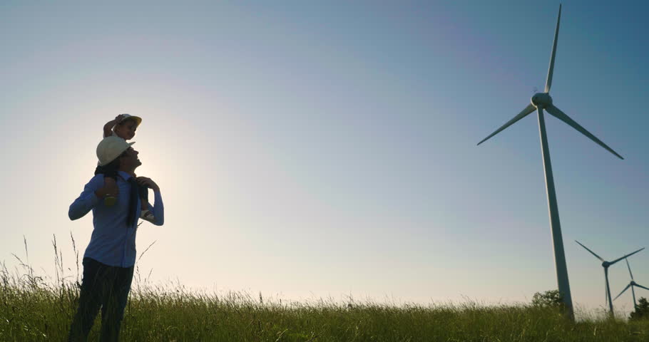 A father engineer holds his daughter in his arms and runs between the wind turbines with great freedom. Concept of: environmental engineering, renewable energy and love for nature and for the family Royalty-Free Stock Footage #1012504964