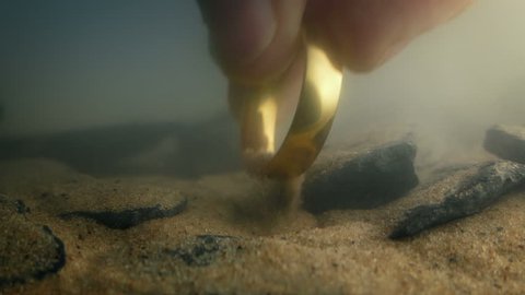 Someone Picks Up Gold Ring From River Bed