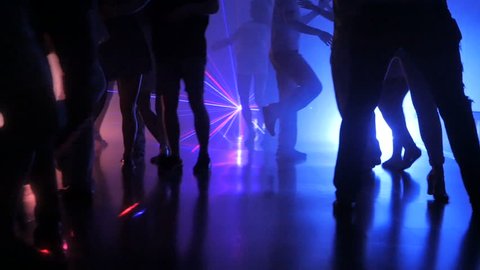 silhouette of legs of dancing people on latino salsa party with multi-colored iridescent lights