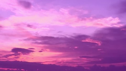 Clouds with orange, purple and black colors at sunset sky. Telephoto video of dramatic pink and purple clouds at sunset. 4K.