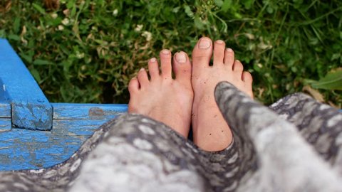 Woman feet barefoot on spring soil, long skirt in wind breeze.