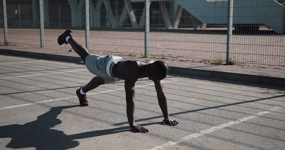 Street workout. Athletic African American man doing push-ups and spin exercise on outdoors. A black man is playing sports near the stadium. Workout, fitness, running, motivation | Shutterstock HD Video #1012521944