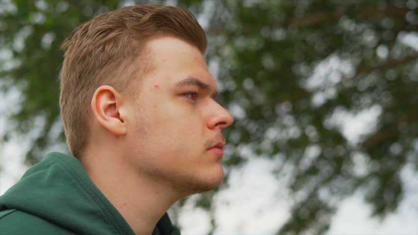 Slow motion portrait close up of A thoughtful man who is staring away from camera near the tree | Shutterstock HD Video #1012528028