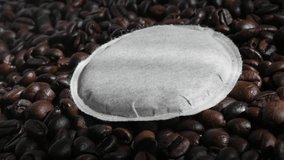 Single filter coffee pod on roasted beans 4K panning footage