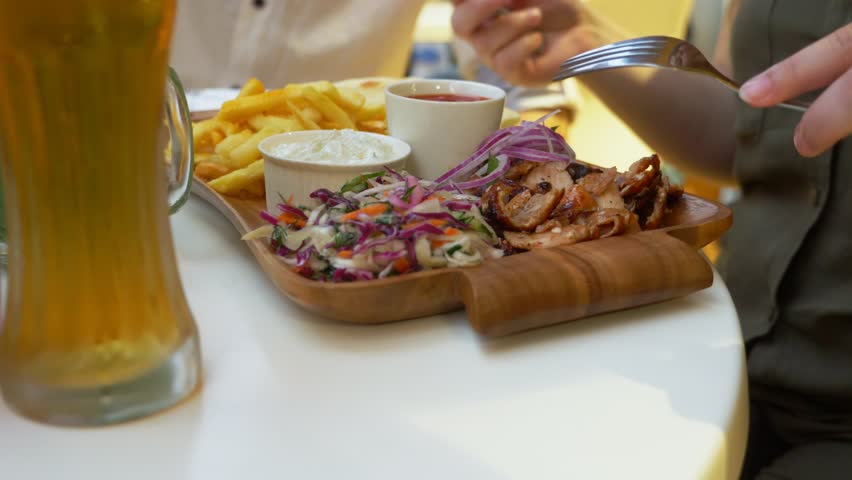a couple, eating in an outdoor cafe Greek dishes, souvlaki and beer. 4k, slow motion