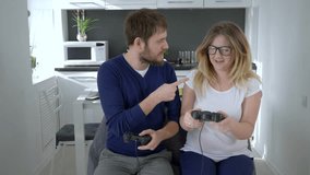 gamers family, husband with wife spectacled compete with each other in video game in kitchen at home