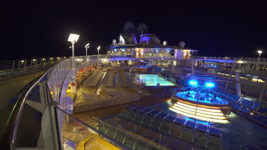 Illuminated cruise ship pool deck at night - March 2018: Harmony of the Seas, Caribbean sea | Shutterstock HD Video #1012549040