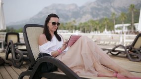 Woman with a tablet resting on a sun lounger on the pier