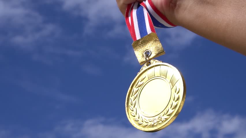 Winners Champion in success award concept : Businessman hands raised holding gold medals with ribbon against blue sky background to show success in sport or business, Slow motion video | Shutterstock HD Video #1012552691