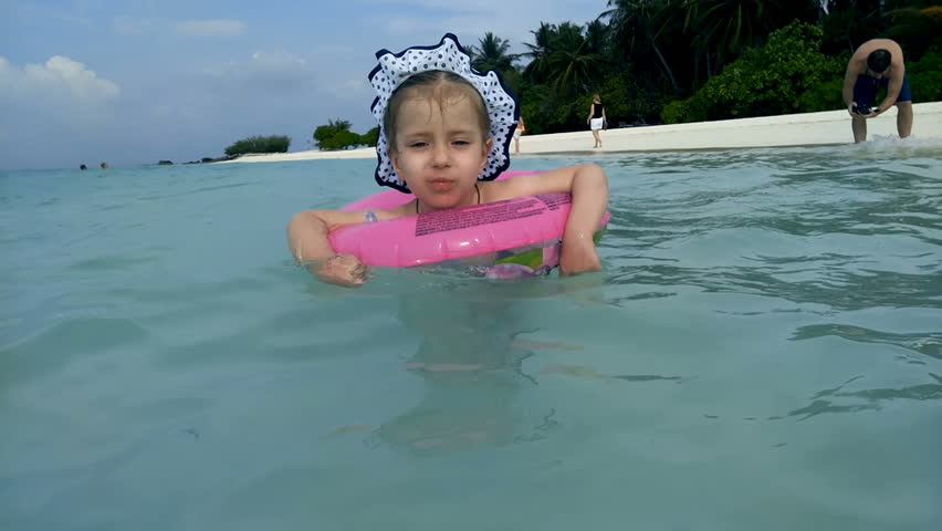 A girl is swimming in the sea with rubber ring for swimming.