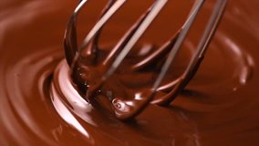 Chocolate. Mixing melted liquid premium dark chocolate with a whisk. Close up of liquid hot chocolate swirl. Confectionery. Confectioner prepares dessert, sauce. 4K UHD video, slow motion 120 fps
